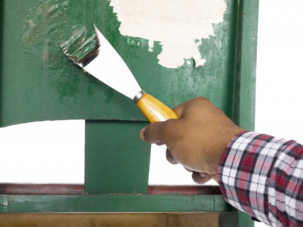 Close-up of man's hand peeling a green paint