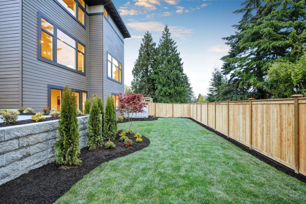 Nice backyard landscape with well kept lawn, flower beds and wooden fence