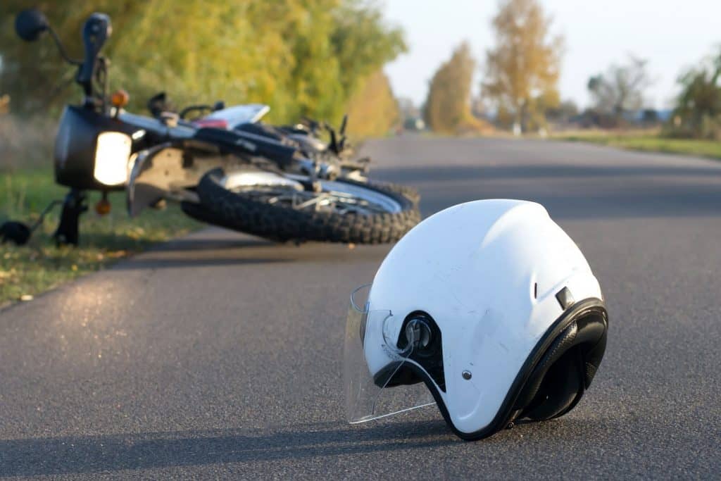 Close up of helmet on the road with crashed motorcycle in the background
