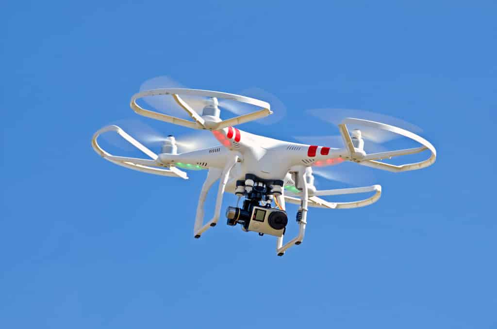 white drone hovering in a bright blue sky