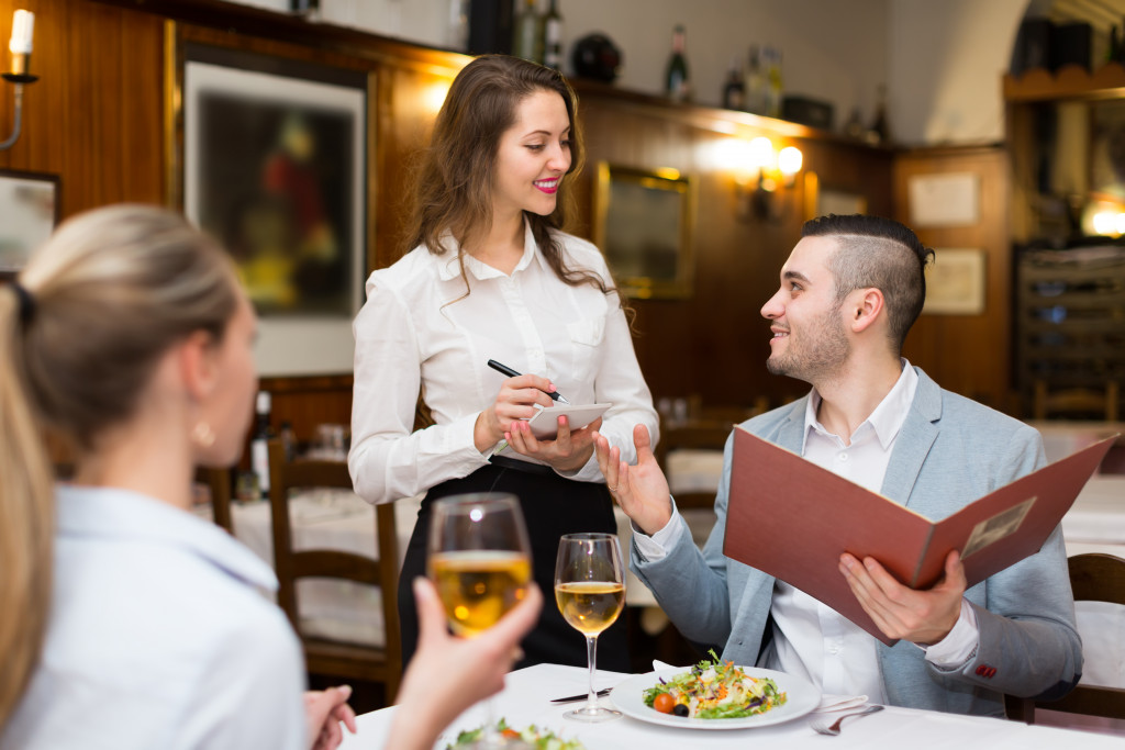 a female waitress talking to diners holding menu