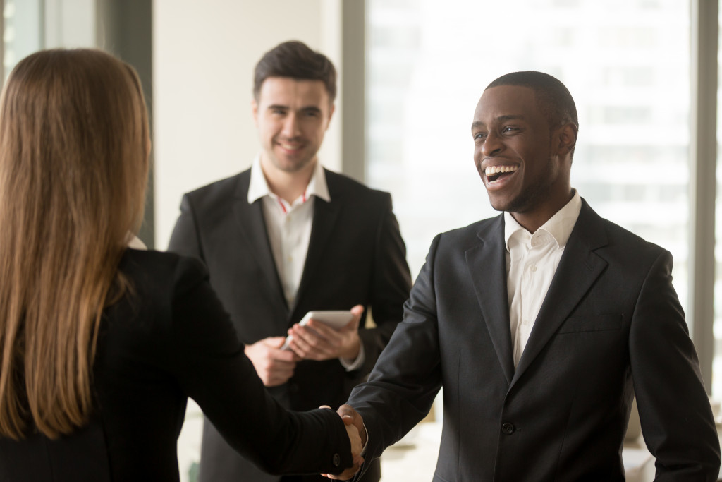 smiling african american businessman and american businesswoman shaking hands