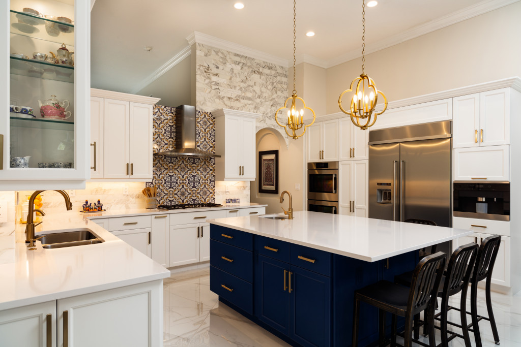 a clean kitchen with blue and white island with two overhead lights hanging from the ceiling and l-shaped countertops