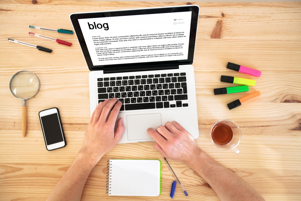 a man using a laptop typing to make a blog