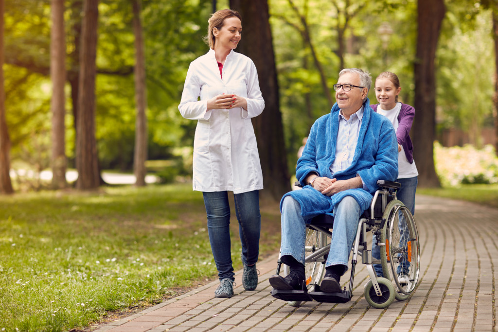 An elderly man on a wheelchair with nurse and grandkid